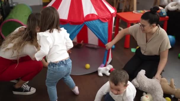 先生と男の子と女の子とサーカステントの上で遊んで床に座って幼稚園 — ストック動画