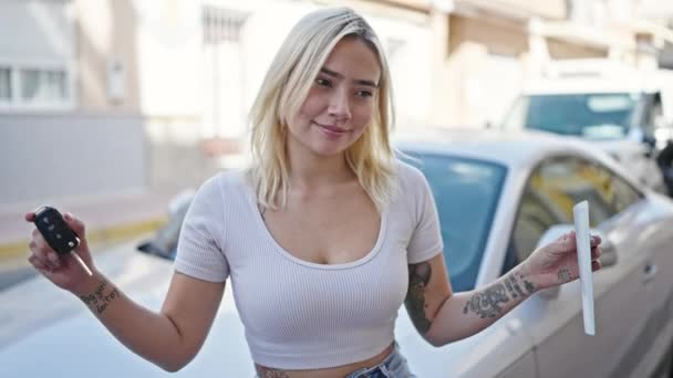 新しい運転免許証とキーを持っている若い美しいヒスパニック系の女性が通りに車で立って — ストック動画