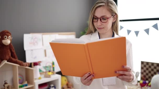 Young Blonde Woman Preschool Teacher Smiling Confident Reading Book Kindergarten — Stockvideo