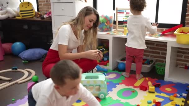 幼稚園でおもちゃで遊んでいる子供たちの先生とグループ — ストック動画