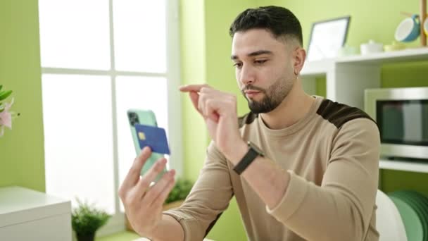 自宅でスマートフォンやクレジットカードを使った若いアラブ人の男のショッピング — ストック動画