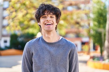 Parkta kendinden emin gülümseyen İspanyol genç adam.