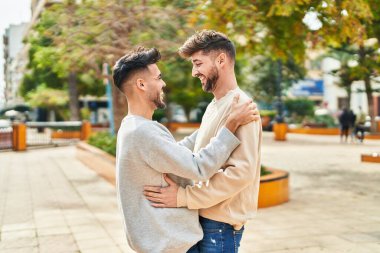 Young couple smiling confident hugging each other at park