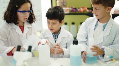 Bir grup öğrenci laboratuvar sınıfında deney yaparak şişenin üzerine sıvı döküyorlar.
