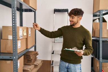 Young arab man ecommerce business worker writing on checklist at office