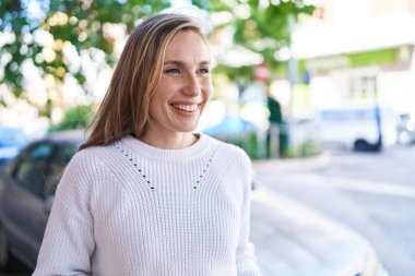 Young blonde woman smiling confident looking to the side at street