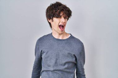 Young man standing over isolated background winking looking at the camera with sexy expression, cheerful and happy face. 