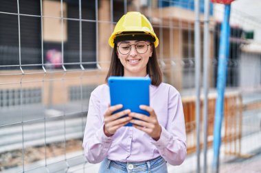 Young hispanic woman architect using touchpad at street