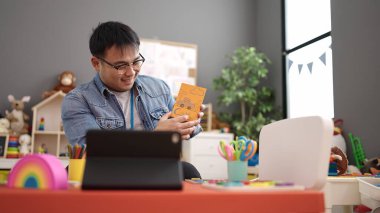 Young chinese man preschool teacher having online vocabulary lesson at kindergarten