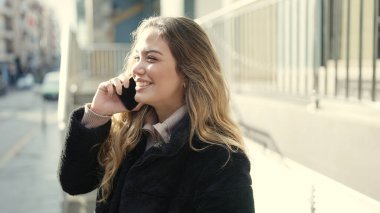 Young beautiful hispanic woman smiling confident talking on smartphone at street