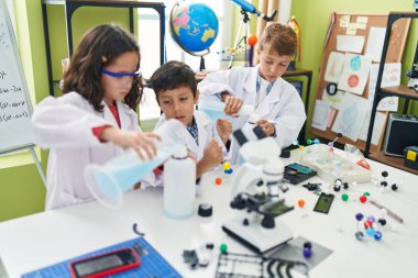 Bir grup öğrenci laboratuvar sınıfında deney yaparak şişenin üzerine sıvı döküyorlar.