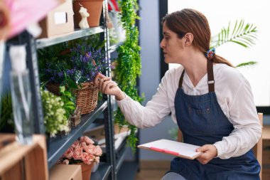 Çiçekçide doküman okuyan genç bir kadın.