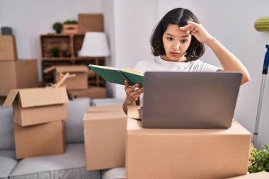 Young woman using laptop with worried expression at new home