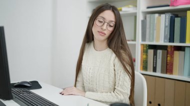 Young beautiful hispanic woman student using computer studying at library university