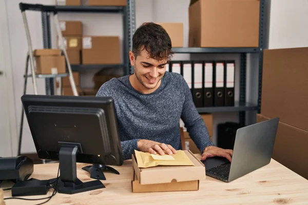 Młody Latynoski Człowiek Commerce Pracownik Pomocą Laptopa Trzymając Pakiety Biurze — Zdjęcie stockowe