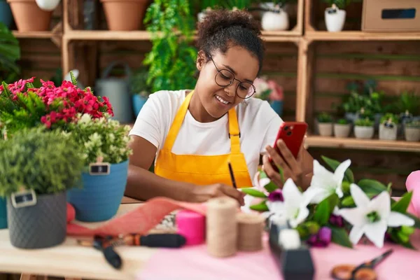 African American Woman Florist Using Smartphone Writing Notebook Flower Shop — Stok fotoğraf