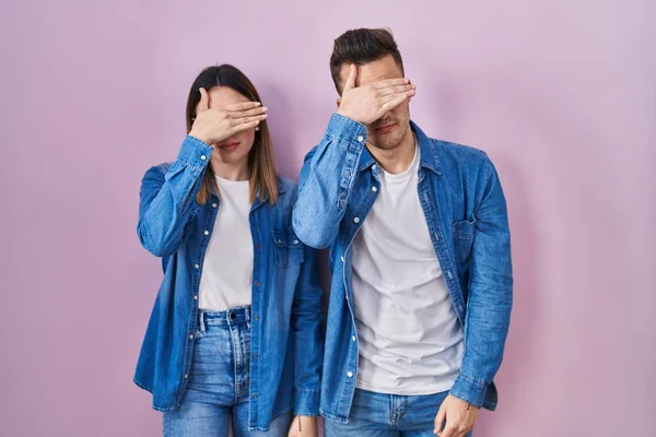 Young Hispanic Couple Standing Pink Background Covering Eyes Hand Looking — Foto Stock