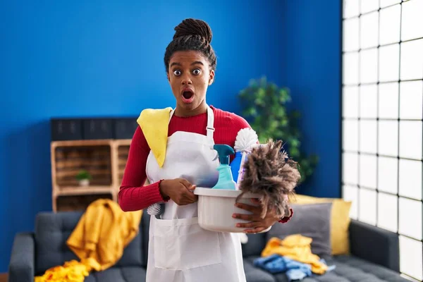 Młody Afroamerykanin Warkoczami Sprzątający Dom Trzymający Środki Czystości Przerażony Zdumiony — Zdjęcie stockowe