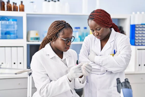 アフリカ系アメリカ人女性科学者が腕を組んで立っているサンプルを見ると — ストック写真