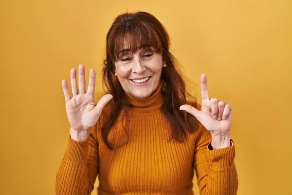 中年惊慌失措的女人站在黄色的背景上 用七号手指指指指点点 自信而快乐地微笑着 — 图库照片