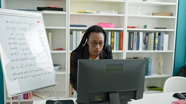 アフリカ系アメリカ人女性教員が大学の教室でコンピュータを使って数学の授業を教えています — ストック写真