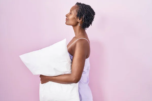 Африканская Женщина Дредами Носить Пижаму Обнимая Подушку Глядя Сторону Расслабиться — стоковое фото