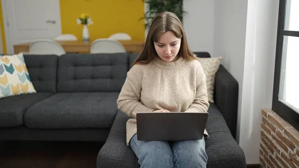 Νεαρή Ξανθιά Γυναίκα Που Χρησιμοποιεί Φορητό Υπολογιστή Κάθεται Στον Καναπέ — Φωτογραφία Αρχείου