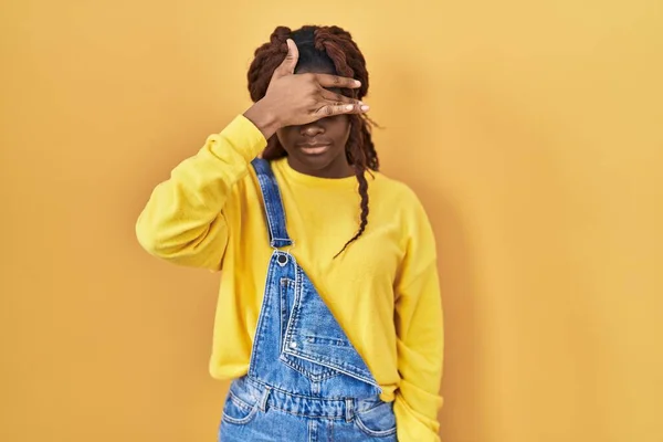 Африканская Женщина Стоящая Жёлтом Фоне Закрывая Глаза Рукой Выглядит Серьезной — стоковое фото