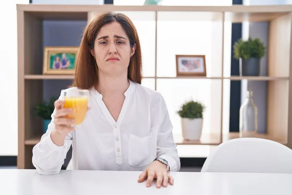 オレンジ色のジュースを飲んでいるブルネットの女性は落ち込んで苦痛を心配し 怒って恐れて泣いています 悲しい表情 — ストック写真