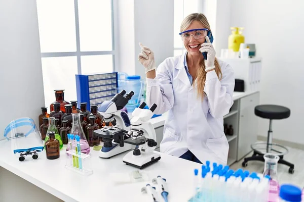 Mulher Bonita Trabalhando Laboratório Cientista Falando Telefone Sorrindo Feliz Apontando — Fotografia de Stock