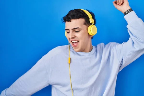 Non binary person listening to music using headphones dancing happy and cheerful, smiling moving casual and confident listening to music