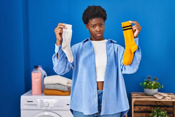 持有干净的安迪脏袜子的非裔美国女人怀疑和紧张 皱着眉头因问题而烦恼 消极的人 — 图库照片