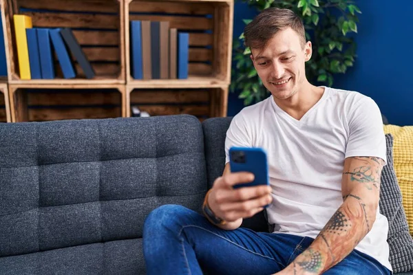 Jovem Usando Smartphone Sentado Sofá Casa — Fotografia de Stock