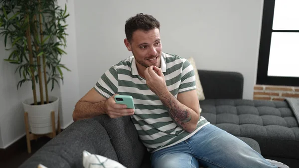 Young Caucasian Man Smiling Using Smartphone Sitting Sofa Home — Stockfoto