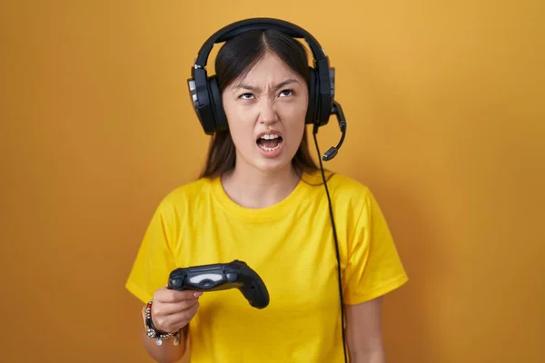 中国的年轻女子在玩电子游戏时 抱着控制器生气而疯狂的尖叫 沮丧而愤怒 怒吼着 愤怒和好斗的概念 — 图库照片