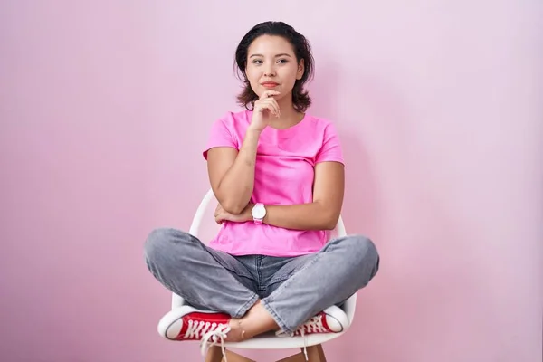Mujer Joven Hispana Sentada Silla Sobre Fondo Rosa Con Mano — Foto de Stock