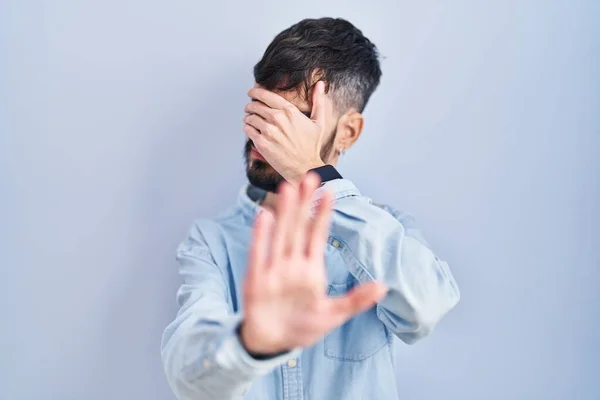 Mavi Arka Planda Sakallı Genç Spanyol Bir Adam Elleriyle Gözlerini — Stok fotoğraf