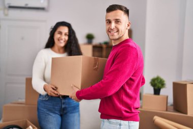 Man and woman couple holding package at new home