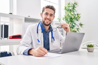 Young man doctor using laptop writing medical report at clinic