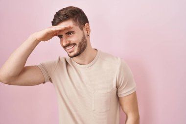 Pembe arka planda duran İspanyol sakallı adam çok mutlu ve gülümsüyor. arama kavramı. 