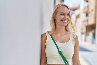 Young blonde woman smiling confident looking to the side at street