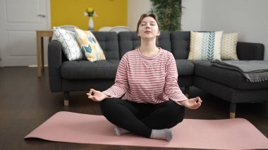 Genç sarışın kadın evde yoga eğitimi veriyor.