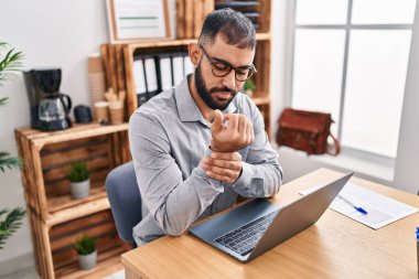 Young hispanic man business worker suffering for wrist pain working at office