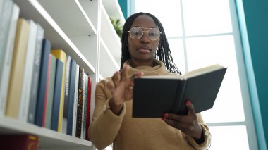 African woman reading a book at library university