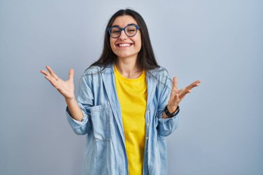 Mavi arka planda duran genç İspanyol kadın çılgın ve başarıyı kollarını kaldırıp heyecanla haykırarak kutluyor. Kazanan konsept 