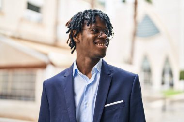 Afro-Amerikalı yönetici gülümseyerek caddede duruyor.