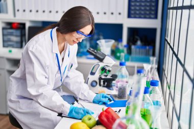 Genç ve güzel İspanyol bilim adamı kahve çekirdeklerini tartıyor. Laboratuvarda rapor yazıyor.