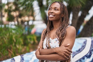 Parkta eli kolu çapraz hareket eden Afrikalı Amerikalı kadın.