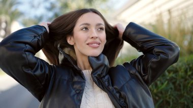 Young beautiful hispanic woman smiling confident combing hair with hands at park