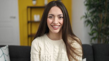 Evdeki kanepede oturan kendine güvenen güzel İspanyol kadın.